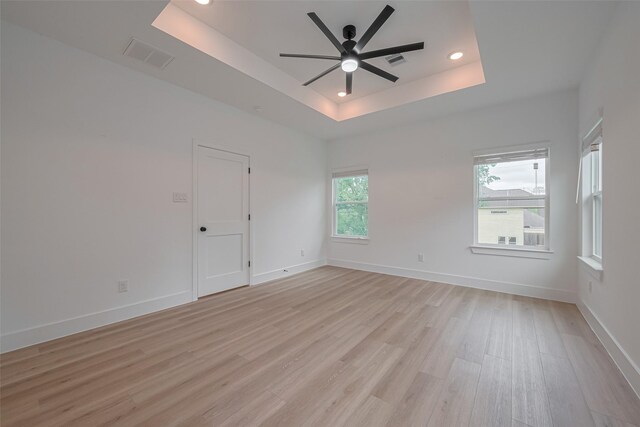 spare room featuring visible vents, recessed lighting, light wood-type flooring, a raised ceiling, and a ceiling fan