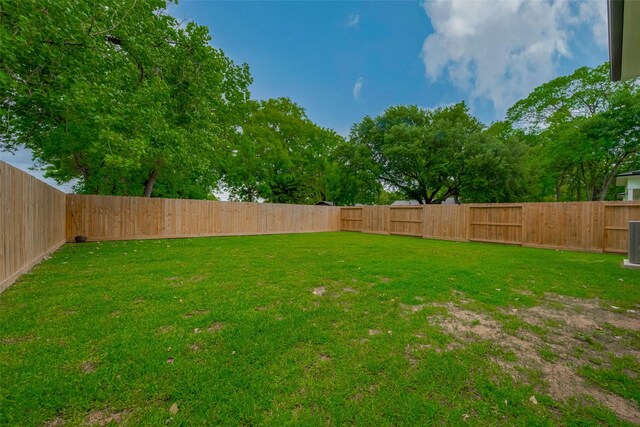 view of yard featuring a fenced backyard and central AC