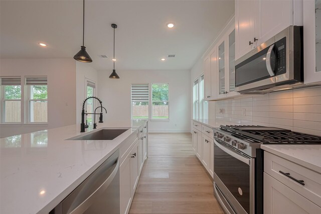 kitchen featuring backsplash, a sink, light stone counters, stainless steel appliances, and recessed lighting