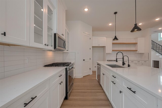 kitchen with a sink, white cabinets, stainless steel appliances, and tasteful backsplash