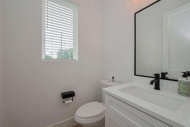 half bath featuring vanity and toilet