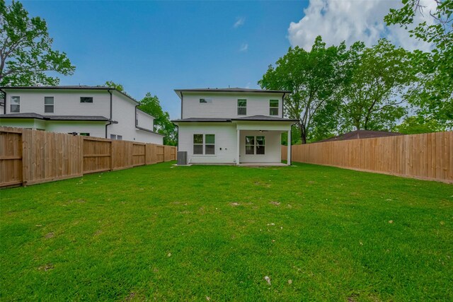 rear view of property featuring a patio, a fenced backyard, a yard, and cooling unit