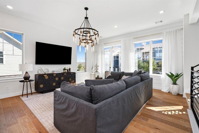 living room featuring baseboards, a notable chandelier, wood finished floors, and visible vents