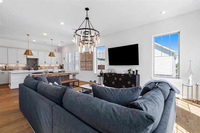 living area featuring an inviting chandelier, recessed lighting, baseboards, and light wood finished floors