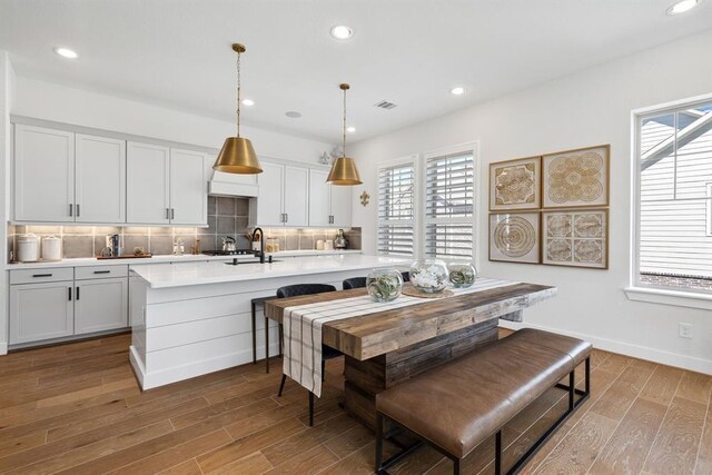 kitchen with backsplash, visible vents, wood finished floors, light countertops, and recessed lighting