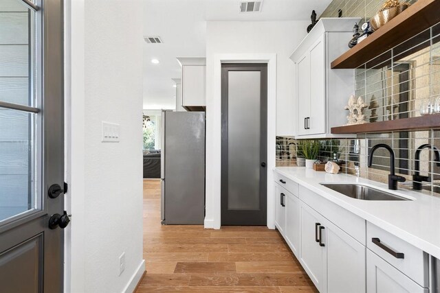 kitchen featuring visible vents, freestanding refrigerator, open shelves, and a sink