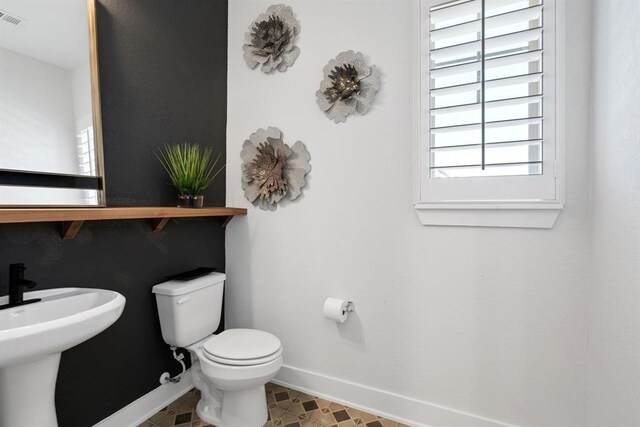 bathroom featuring toilet, baseboards, visible vents, and a sink