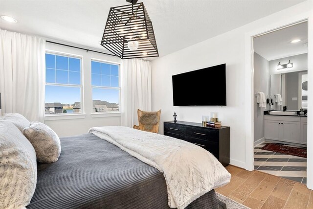 bedroom with light wood-style floors, baseboards, recessed lighting, and ensuite bath
