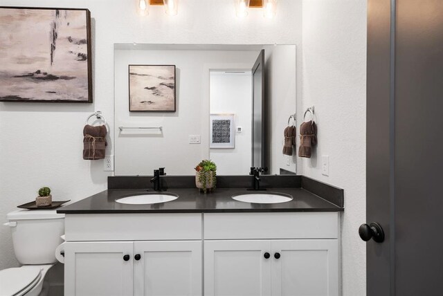 full bath with double vanity, a sink, and toilet