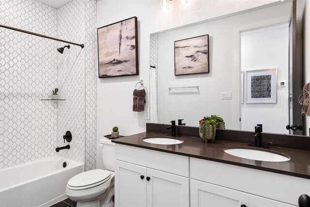 bathroom with double vanity, a sink, washtub / shower combination, and toilet