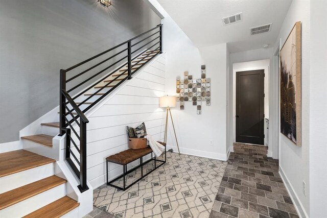 entryway featuring baseboards, visible vents, and stairway