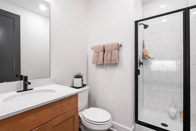 bathroom with vanity, a shower stall, and toilet