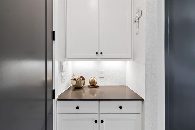 interior space featuring white cabinetry, dark countertops, and a textured wall