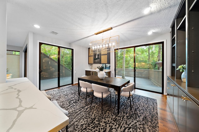 dining room featuring dark wood-type flooring, a chandelier, a textured ceiling, and recessed lighting