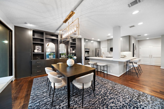dining room with dark wood finished floors, a textured ceiling, recessed lighting, and a chandelier