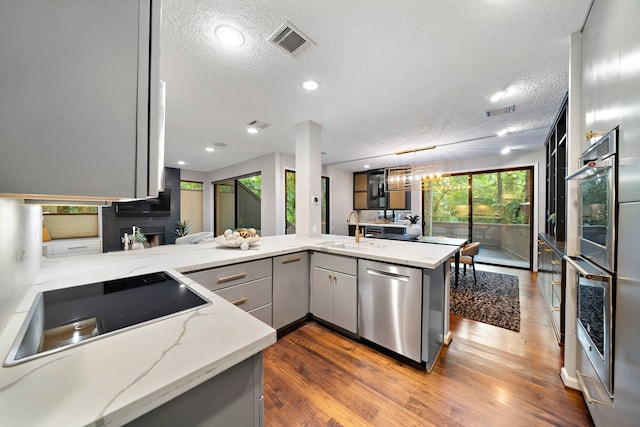 kitchen featuring a sink, appliances with stainless steel finishes, gray cabinets, a textured ceiling, and dark wood-style flooring