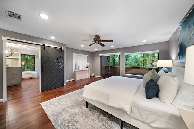 bedroom featuring a barn door, multiple windows, recessed lighting, and dark wood finished floors
