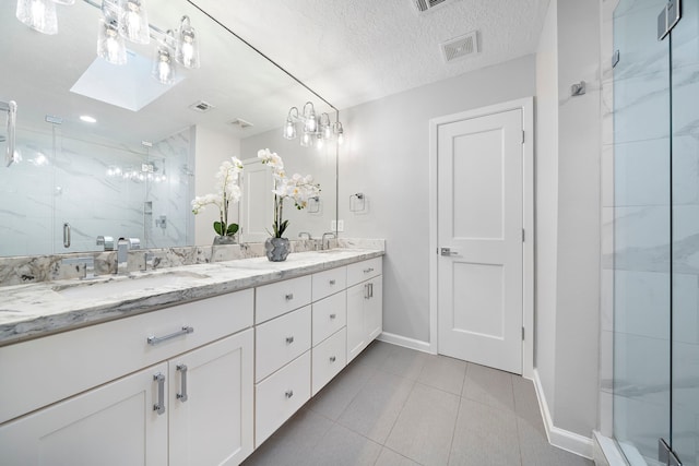 full bathroom featuring a marble finish shower, baseboards, double vanity, tile patterned flooring, and a textured ceiling