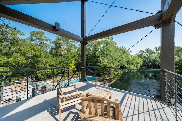 view of patio / terrace featuring a balcony, view of scattered trees, and a water view
