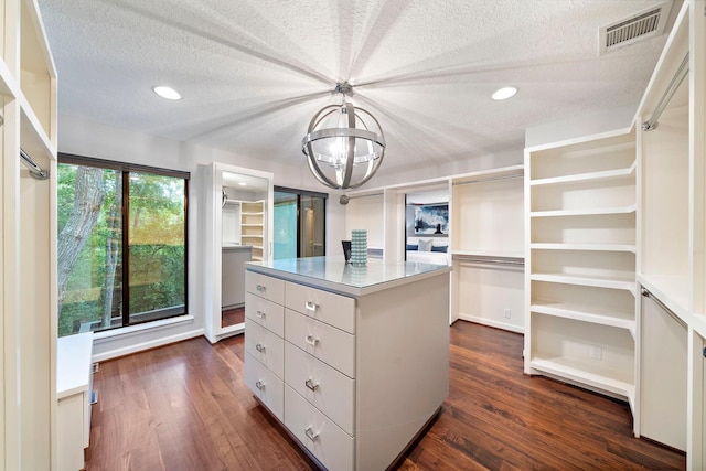 walk in closet featuring dark wood finished floors and a chandelier