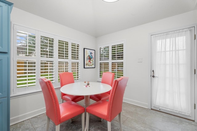 dining space with a healthy amount of sunlight, baseboards, and vaulted ceiling