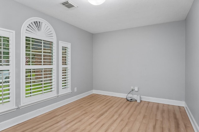 empty room with baseboards, visible vents, and wood finished floors