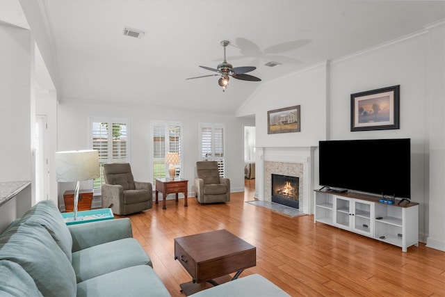 living room with a ceiling fan, a warm lit fireplace, visible vents, and lofted ceiling