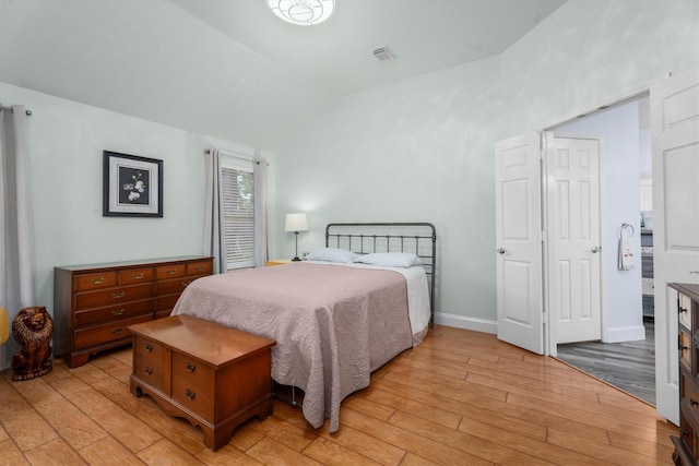 bedroom with baseboards, visible vents, light wood-type flooring, and lofted ceiling