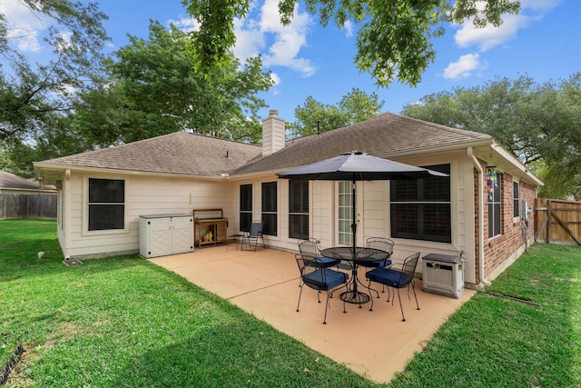 rear view of property with a chimney, roof with shingles, a lawn, a patio area, and fence