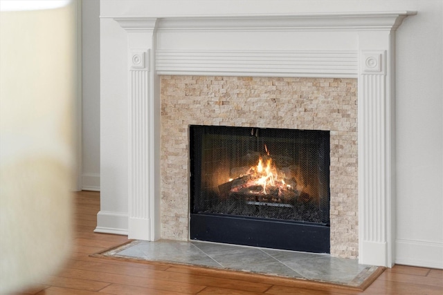 interior details featuring a tiled fireplace, baseboards, and wood finished floors