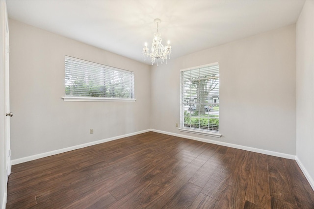 unfurnished room with baseboards, an inviting chandelier, and dark wood-type flooring