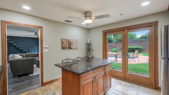 kitchen with visible vents, stone tile flooring, freestanding refrigerator, french doors, and a ceiling fan