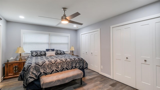 bedroom with wood finished floors, recessed lighting, ceiling fan, and two closets