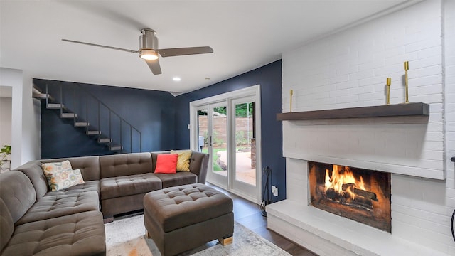 living room with ceiling fan, wood finished floors, stairway, and a fireplace