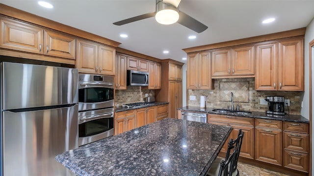 kitchen featuring a ceiling fan, a kitchen island, tasteful backsplash, a sink, and stainless steel appliances