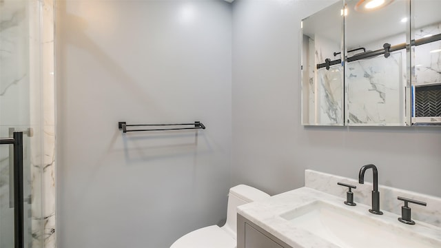 bathroom with vanity, a marble finish shower, and toilet