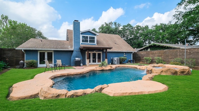 view of swimming pool with french doors, a yard, and a fenced backyard