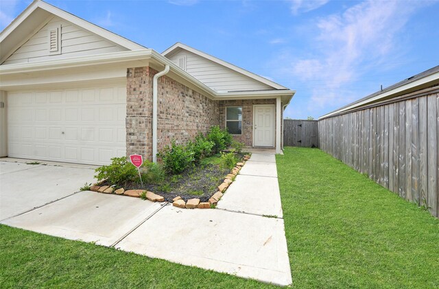 view of front of home featuring driveway, a front yard, brick siding, fence, and an attached garage