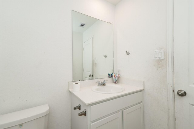 bathroom with vanity, toilet, and visible vents
