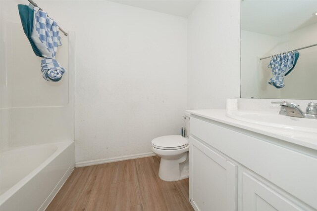 bathroom featuring shower / tub combo with curtain, vanity, toilet, baseboards, and wood finished floors