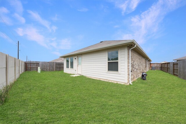 back of property with a fenced backyard and a yard