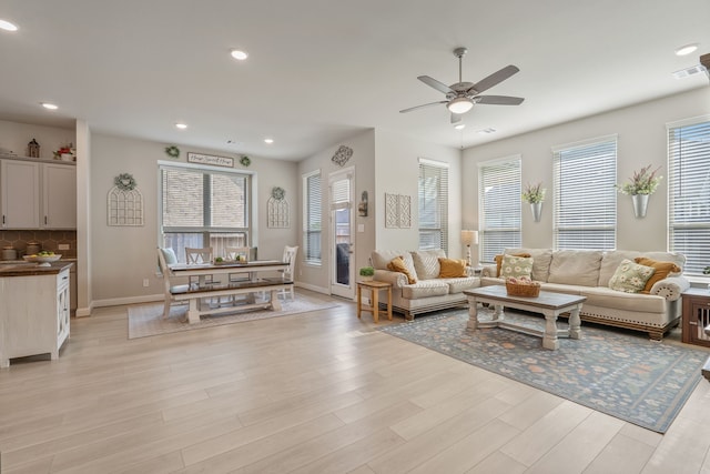 living room featuring visible vents, baseboards, ceiling fan, recessed lighting, and light wood finished floors