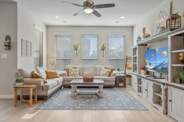 living room featuring baseboards, ceiling fan, light wood-type flooring, and visible vents