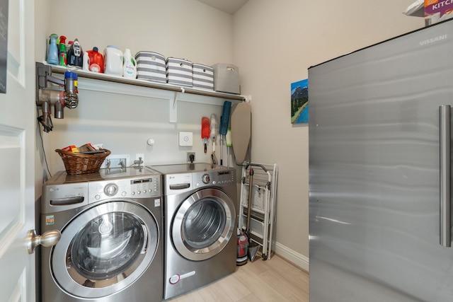 laundry room with baseboards, laundry area, washing machine and dryer, and light wood-type flooring