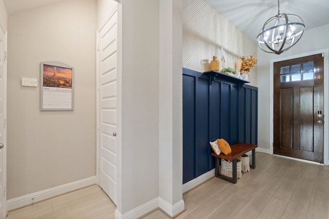 entrance foyer featuring light wood-type flooring, baseboards, and a notable chandelier