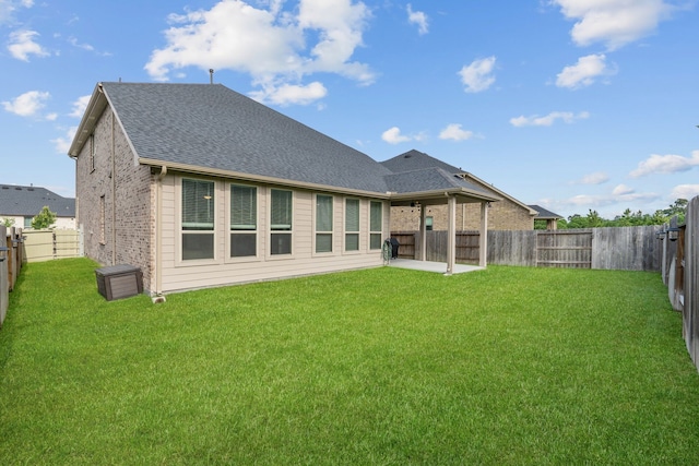 back of property featuring a fenced backyard, a yard, a patio area, and roof with shingles