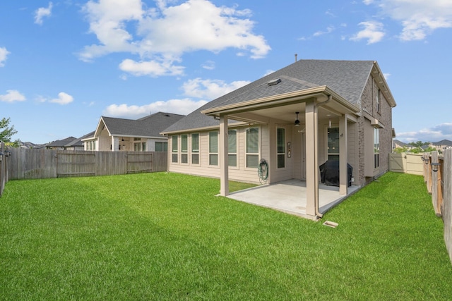 back of house featuring a fenced backyard, roof with shingles, a ceiling fan, a patio area, and a yard