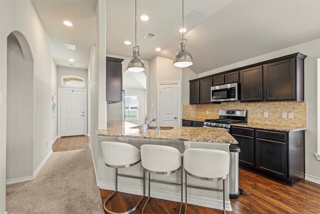 kitchen with visible vents, light stone countertops, a breakfast bar area, appliances with stainless steel finishes, and backsplash