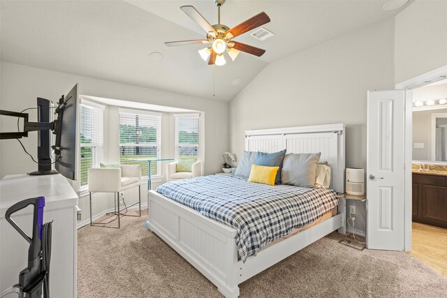 bedroom featuring visible vents, a sink, vaulted ceiling, and light carpet