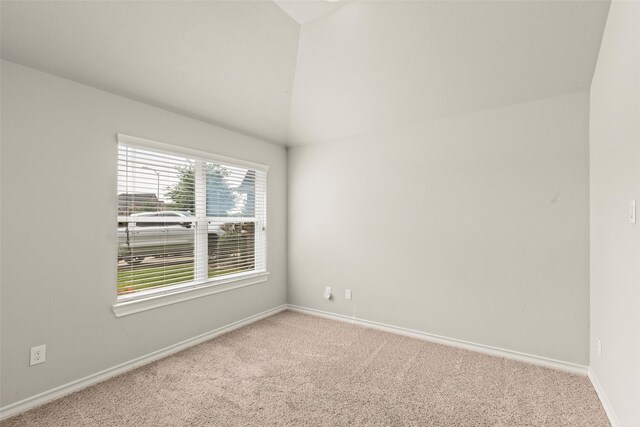 carpeted empty room with baseboards and lofted ceiling